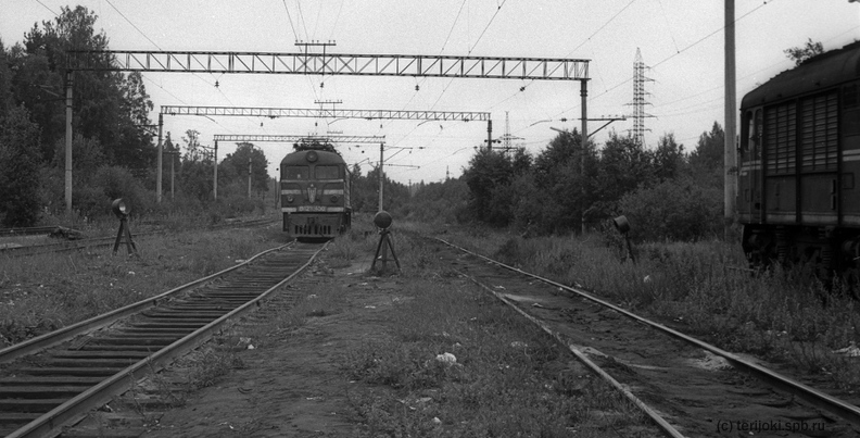 Электровоз ВЛ23-430 на путях пункта оборота локомотивов станции Кузнечное. В правой части кадра - силуэт пассажирского тепловоза серии ТЭП60, ожидающего прибытия поезда № 249 Ленинград-Костомукша. Фото: Михаил Нагибин, 30 июля 1990 г. mn_VL23-430_1990_07_30.jpg